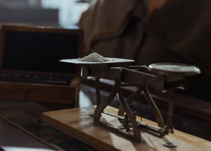 Classic vintage weighing scale with a small heap of white powder placed indoors on a wooden surface.