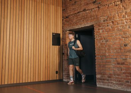 A sporty man leaving a brick-walled sports hall, embodying active lifestyle and fitness.